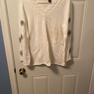 White sweater with designs on the arms